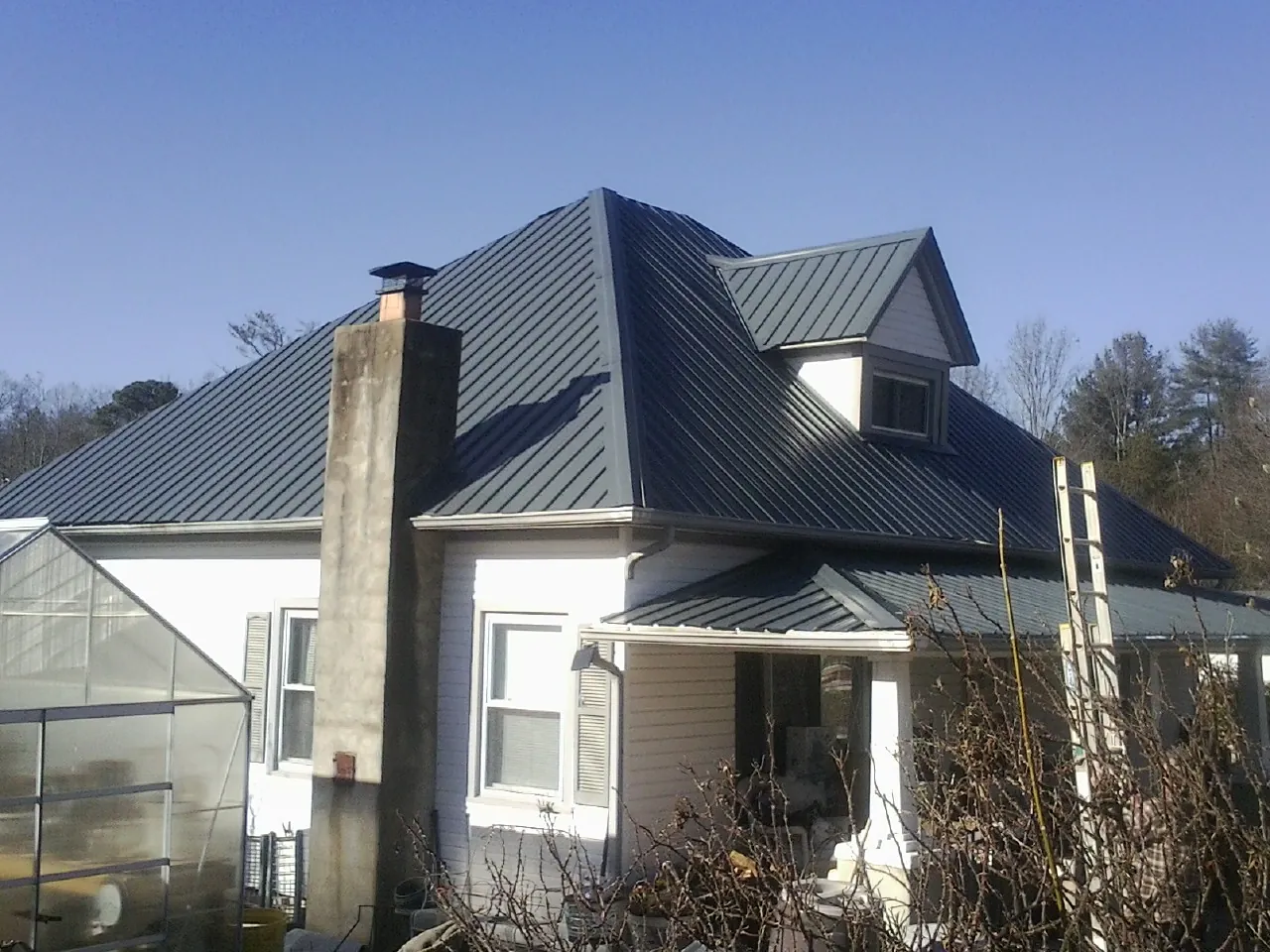 Dark blue standing seam metal roof on a white farmhouse with dormer — Slate & Tile Roof Repair by Roofing Brothers in Palmersville
