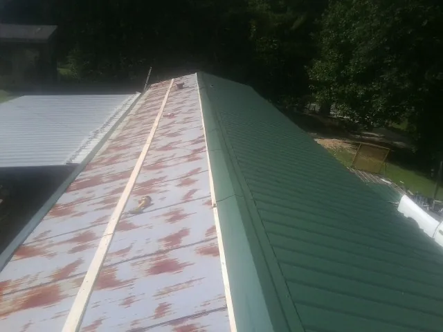 Old rusted panels beside newly installed green metal roofing — Wind Damage Roof Repair by Roofing Brothers in Palmersville