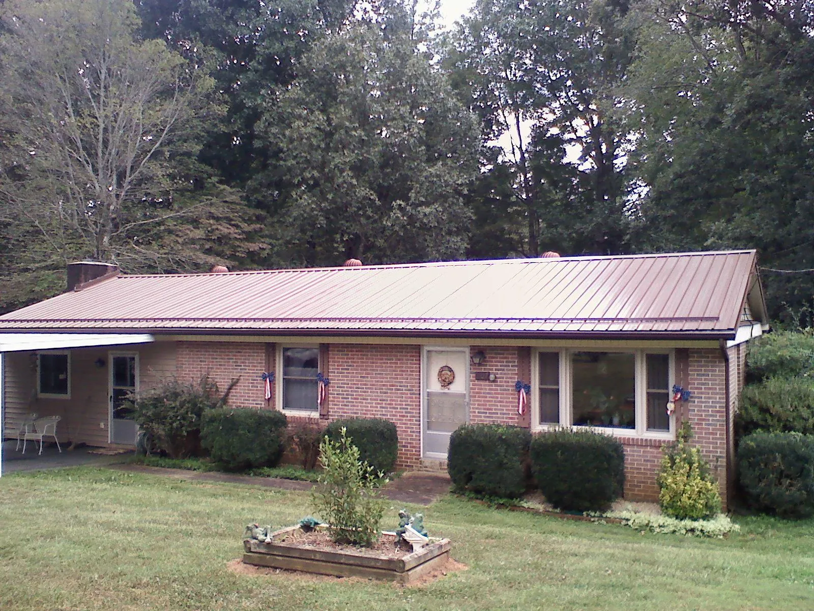 Bronze metal roof on a brick ranch home with a carport in Palmersville