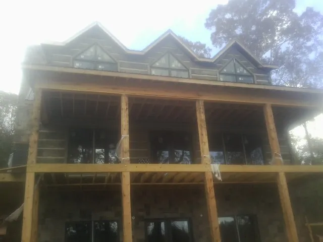 Dormers and porch framing on a large log home under construction — Roof Coating work by our crew in Palmersville