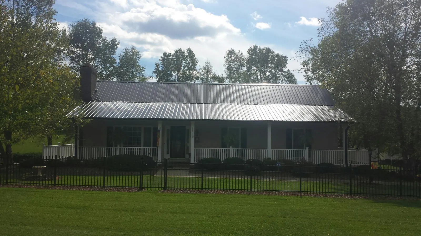 Gray metal roof on a brick ranch with a full width front porch — Gutter Guard Installation work by our crew in Palmersville