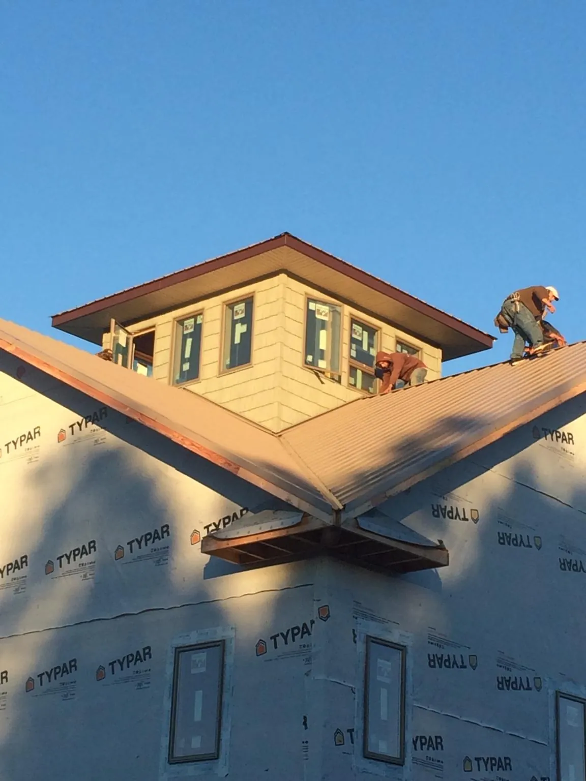 Roofers working around a rooftop cupola on a new metal roof at sunset — Roof Waterproofing in Palmersville by Roofing Brothers
